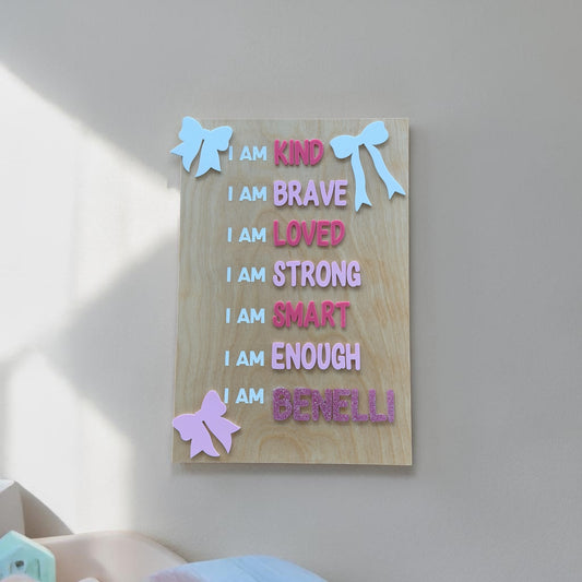 Personalized kids affirmation sign hanging on wall with custom name and pastel acrylic bows